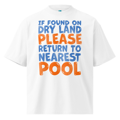 A white short-sleeve crewneck organic oversized t-shirt featuring a colorful graphic text print that reads 'IF FOUND ON DRY LAND PLEASE RETURN TO NEAREST POOL' in blue and orange bubble lettering.