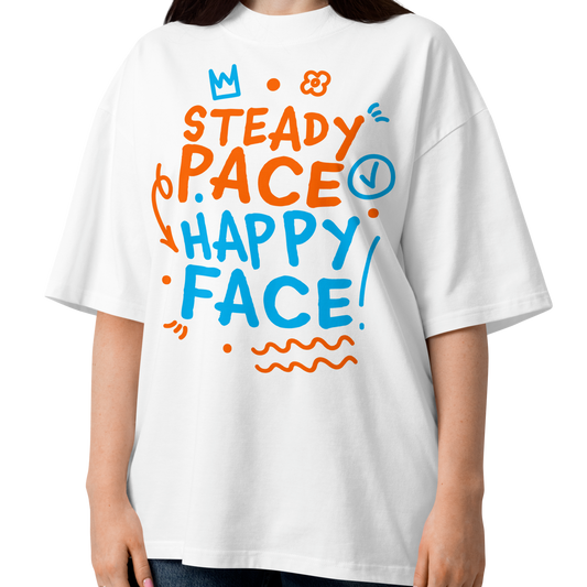 A woman modeling a white short-sleeve crewneck organic oversized t-shirt by Lane Line Threads featuring a colorful graphic print on the front with the words 'STEADY PACE HAPPY FACE' in orange and blue hand-drawn lettering.