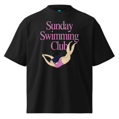 A black short-sleeve crewneck organic oversized t-shirt featuring a graphic print on the front with the text 'Sunday Swimming Club' in pink and an illustration of a woman diving underwater.