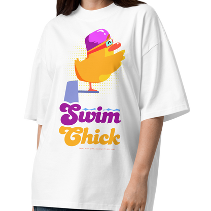 A woman modeling a white short-sleeve crewneck organic oversized t-shirt by Lane Line Threads featuring a colorful graphic of a yellow duck wearing a purple swim cap and goggles, with the text 'Swim Chick' printed below in purple and orange, paired with dark blue jeans and brown sandals, against a plain white background.