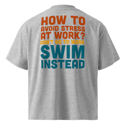 A gray short-sleeve organic oversized t-shirt by Lane Line Threads, shown from the back, featuring a bold typographic graphic in orange, yellow, and teal that reads, 'HOW TO AVOID STRESS AT WORK? DON'T GO TO WORK SWIM INSTEAD'.