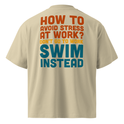 Beige short-sleeve organic oversized t-shirt by Lane Line Threads, shown from the back, featuring a bold typographic graphic in orange, yellow, and teal that reads, 'HOW TO AVOID STRESS AT WORK? DON'T GO TO WORK SWIM INSTEAD'.