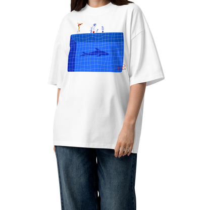 A young woman modeling a white short-sleeve crewneck organic oversized t-shirt by Lane Line Threads for swimmers featuring a graphic print of a blue swimming pool with a diving board, a diver, plants, and a shark on the front.