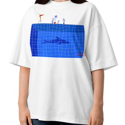 A woman modeling a white short-sleeve crewneck organic oversized t-shirt by Lane Line Threads for swimmers featuring a graphic print of a blue swimming pool with a diving board, a diver, plants, and a shark on the front.