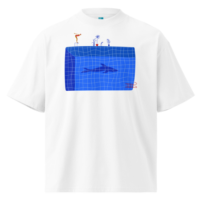 A white short-sleeve crewneck organic oversized t-shirt by Lane Line Threads for swimmers featuring a graphic print of a blue swimming pool with a diving board, a diver, plants, and a shark on the front.