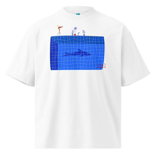 A white short-sleeve crewneck organic oversized t-shirt by Lane Line Threads for swimmers featuring a graphic print of a blue swimming pool with a diving board, a diver, plants, and a shark on the front.