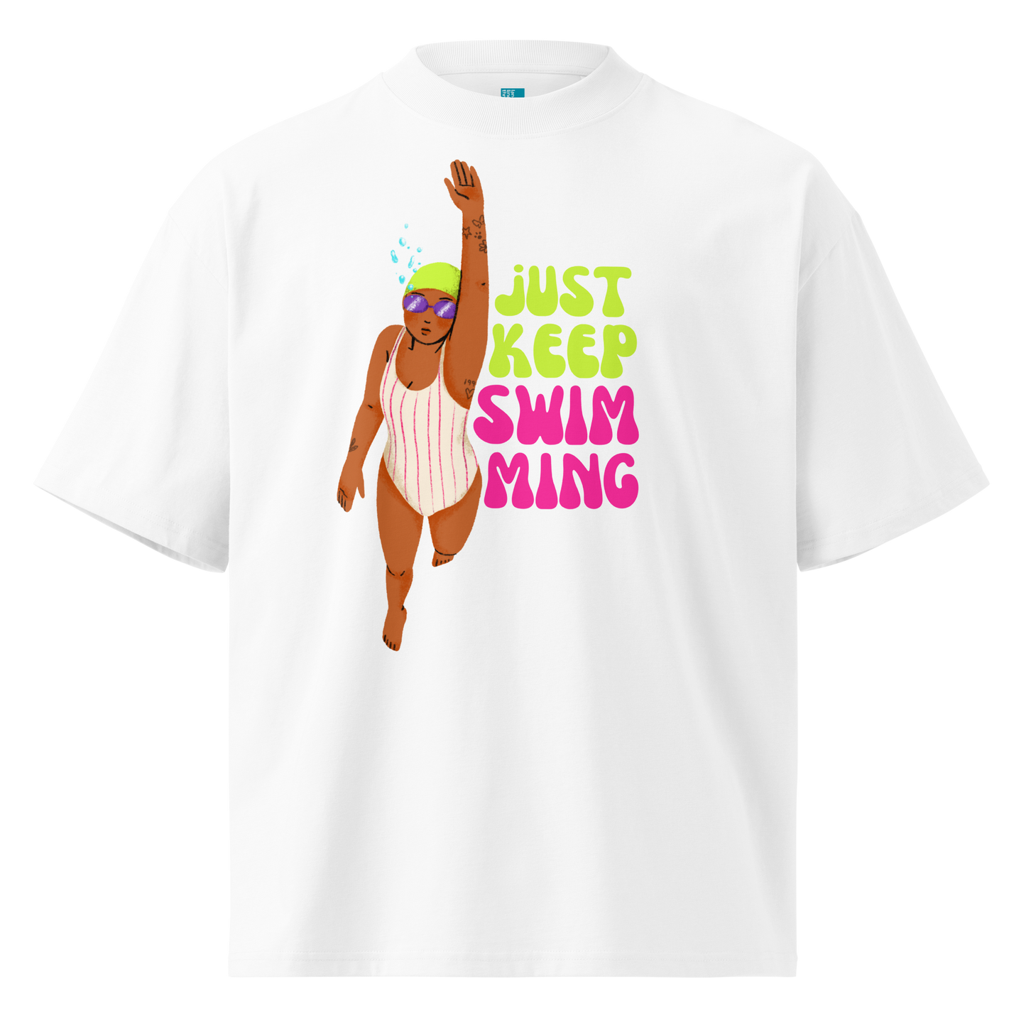 A white short-sleeve crewneck organic oversized t-shirt featuring a colorful graphic of a girl swimmer next to the text 'JUST KEEP SWIM MING' in lime green and pink.