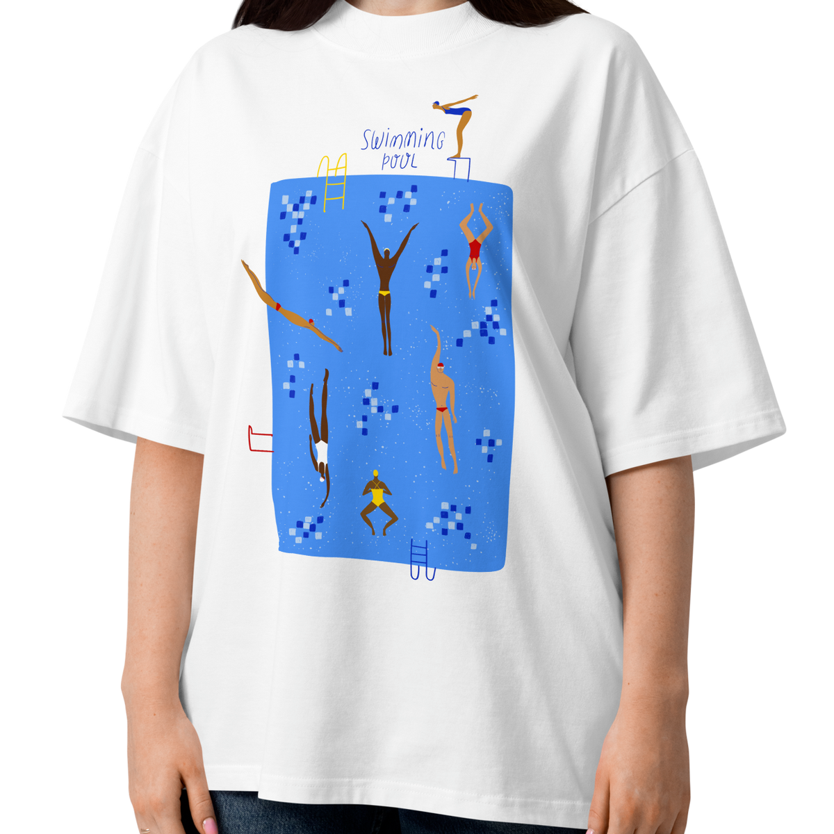 A woman modeling a white short-sleeve crewneck organic oversized t-shirt by Lane Line Threads featuring a colorful graphic print of a swimming pool with various stylized swimmers and divers on a clean background.
