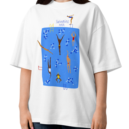 A woman modeling a white short-sleeve crewneck organic oversized t-shirt by Lane Line Threads featuring a colorful graphic print of a swimming pool with various stylized swimmers and divers on a clean background.