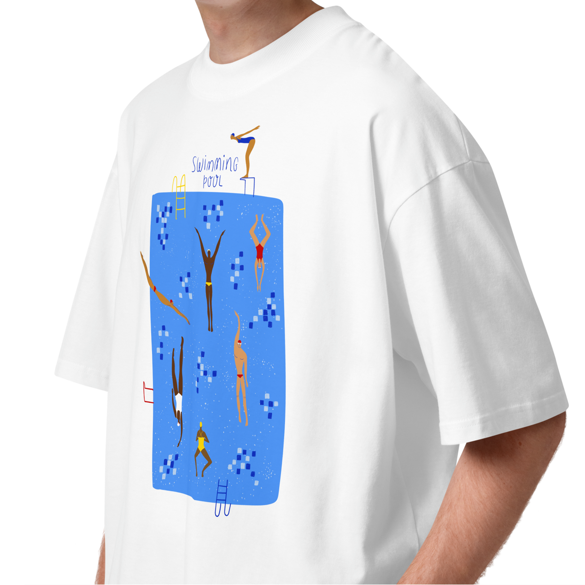 A young man with curly brown hair wearing a white short-sleeve crewneck organic oversized t-shirt by Lane Line Threads featuring a colorful graphic print of a swimming pool with various stylized swimmers and divers on a clean background.