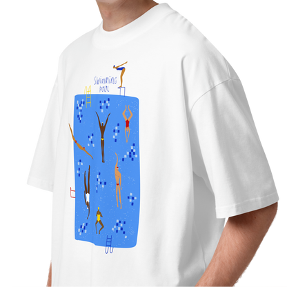 A young man with curly brown hair wearing a white short-sleeve crewneck organic oversized t-shirt by Lane Line Threads featuring a colorful graphic print of a swimming pool with various stylized swimmers and divers on a clean background.