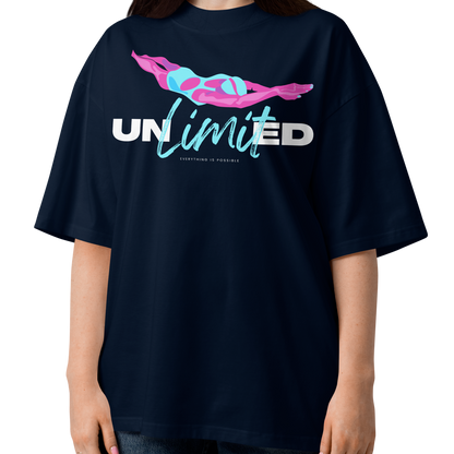 A woman modeling a navy blue short-sleeve organic oversized t-shirt by Lane Line Threads with a graphic on the chest featuring a pink and blue female swimmer silhouette above the text 'UNlimited' in white and light blue.