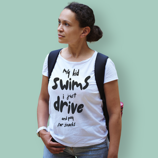 Woman wearing a white organic swim mom shirt with text, standing against a light green background