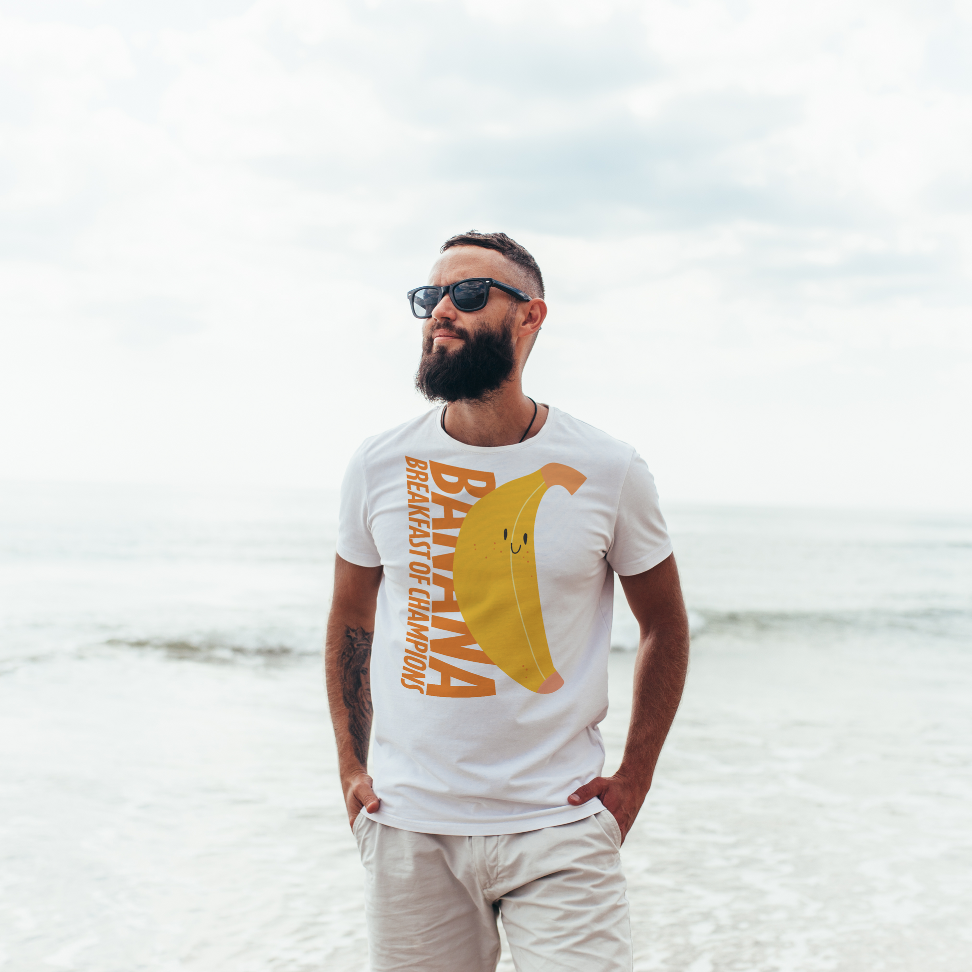 Man wearing a white organic swim shirt with a yellow graphic on a beach