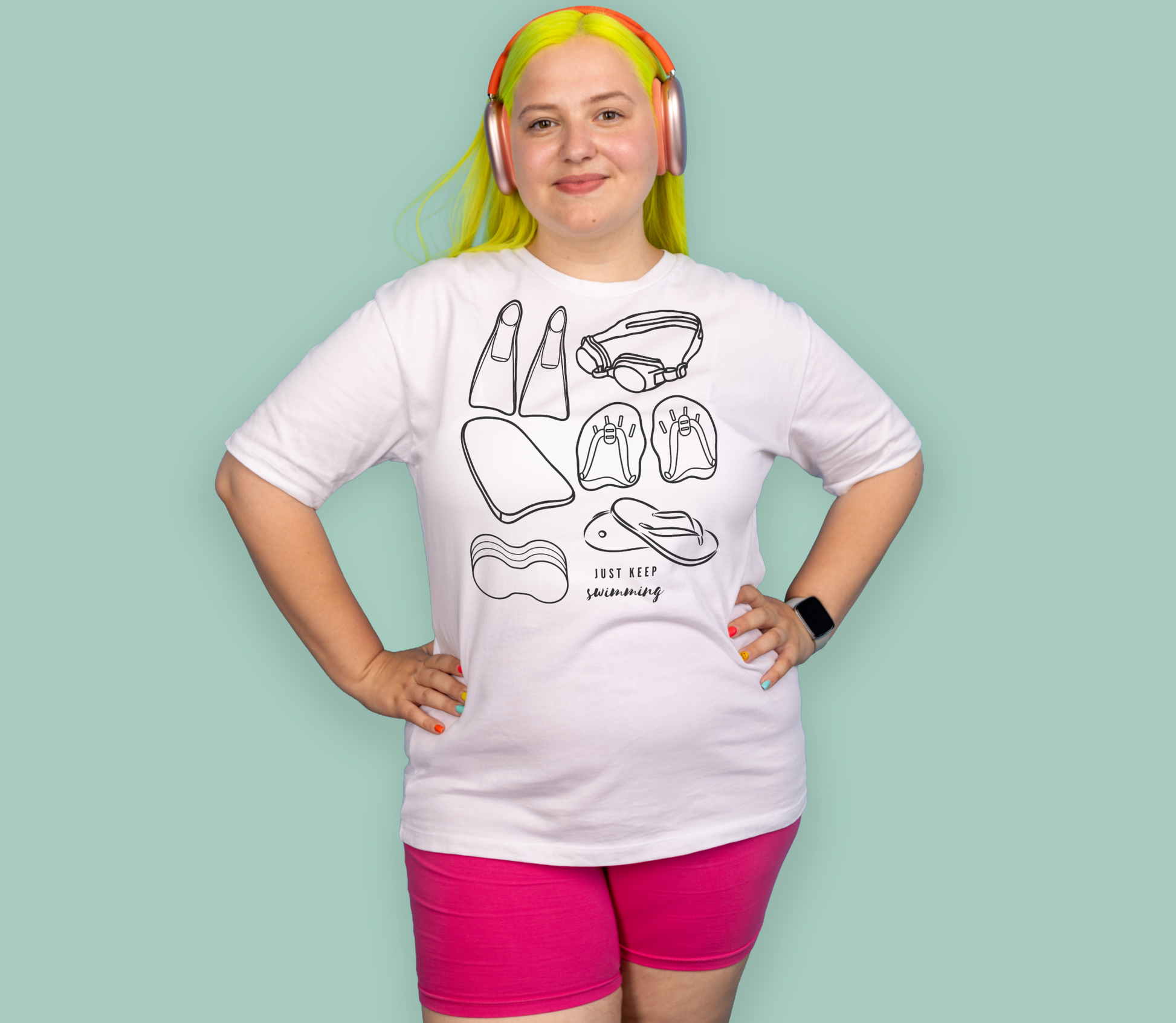 Person wearing a white organic swim shirt with black line art of swimming gear designs and pink shorts on a light green background