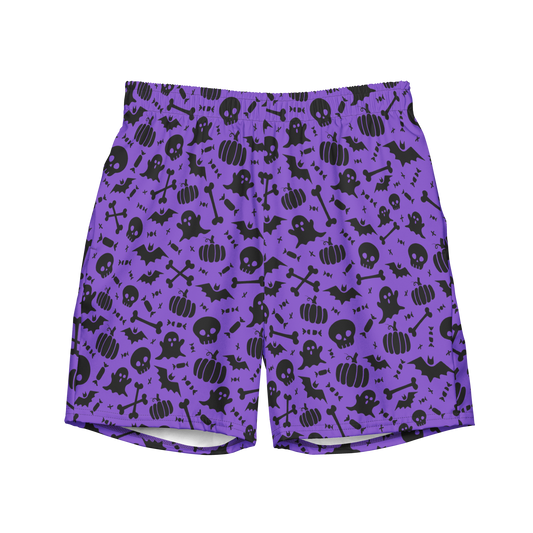 A pair of purple organic swim trunks with a repeating pattern of black Halloween-themed graphics including ghosts, pumpkins, skulls, bats, and bones. 