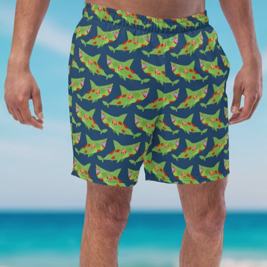 Men wearing organic swim trunks with green zombie sharks' pattern staying on the beach Infront of the ocean