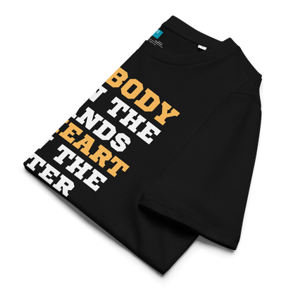 Black organic cotton swim mom t-shirt with bold text: “My Body Is in the Stands, My Heart Is in the Water,” displayed on transparent background folded