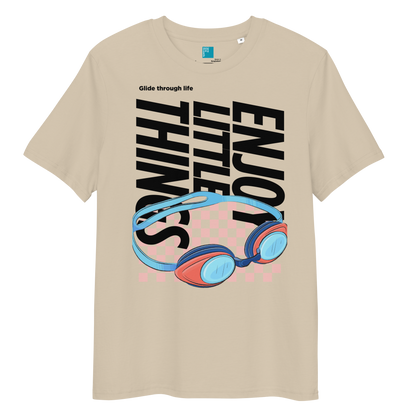 Desert dust eco-friendly t-shirt featuring vibrant blue and red swimming goggles with a checkered background, and bold black text "ENJOY THE LITTLE THINGS" rotated vertically. Above the goggles, "Glide through life" is in smaller text. Made from 100% organic cotton, this breathable and biodegradable shirt is perfect for competitive swimmers who value comfort, performance, and sustainability. Ideal gift for swim meets or lane-protecting athletes with a sense of humor.