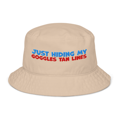 Beige organic bucket hat with blue and red embroidery reading “Just Hiding My Goggles Tan Lines.” Eco-friendly, breathable, and biodegradable swimmer hat.