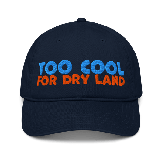 Navy blue organic cotton baseball cap embroidered with “Too Cool for Dry Land” in bold blue and orange text. Eco-friendly, breathable, and biodegradable.